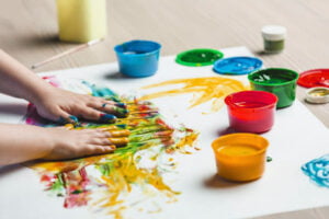 Enfant les mains pleines de peinture réalisant une composition artistique